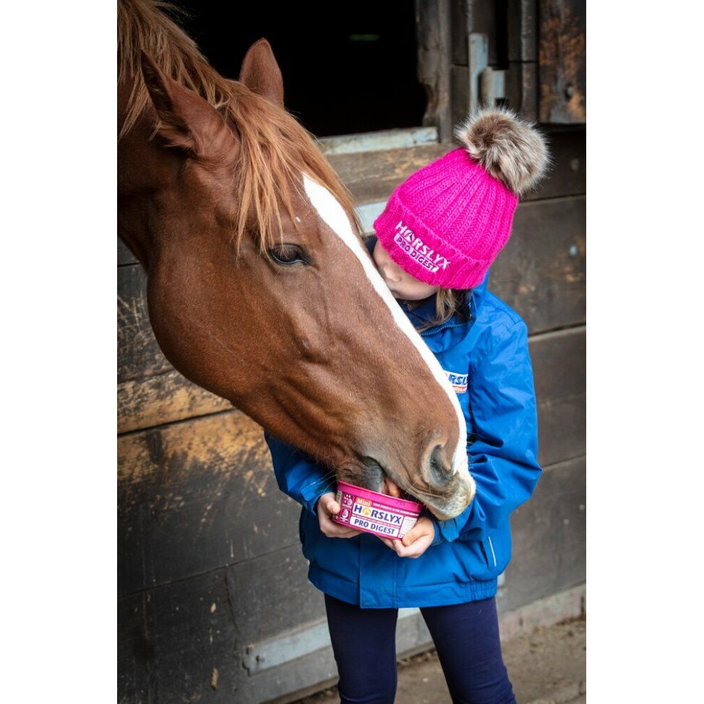 Kind mit Mütze und Pferd. Das Kind hält eine rosa Leckmasse mit der Aufschrift HORSLYX PRO DIGEST.