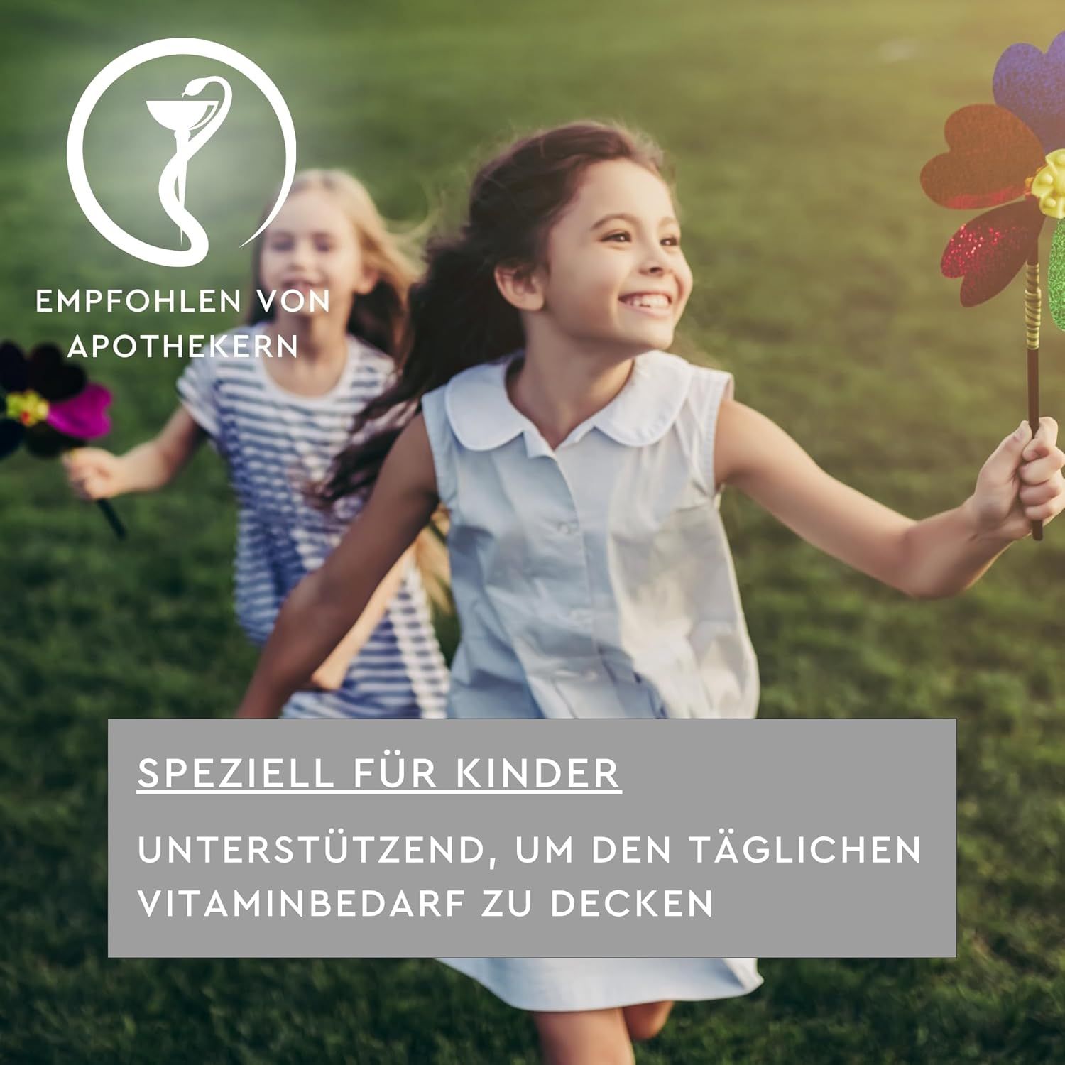 Zwei lächelnde Kinder mit Windrädern auf einer Wiese. Text: Empfohlen von Apothekern. Speziell für Kinder. Unterstützend, um den täglichen Vitaminbedarf zu decken.