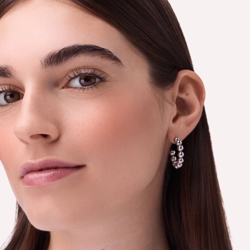 Nahaufnahme eines Gesichts mit Rouge auf den Wangen. Person trägt Ohrringe.