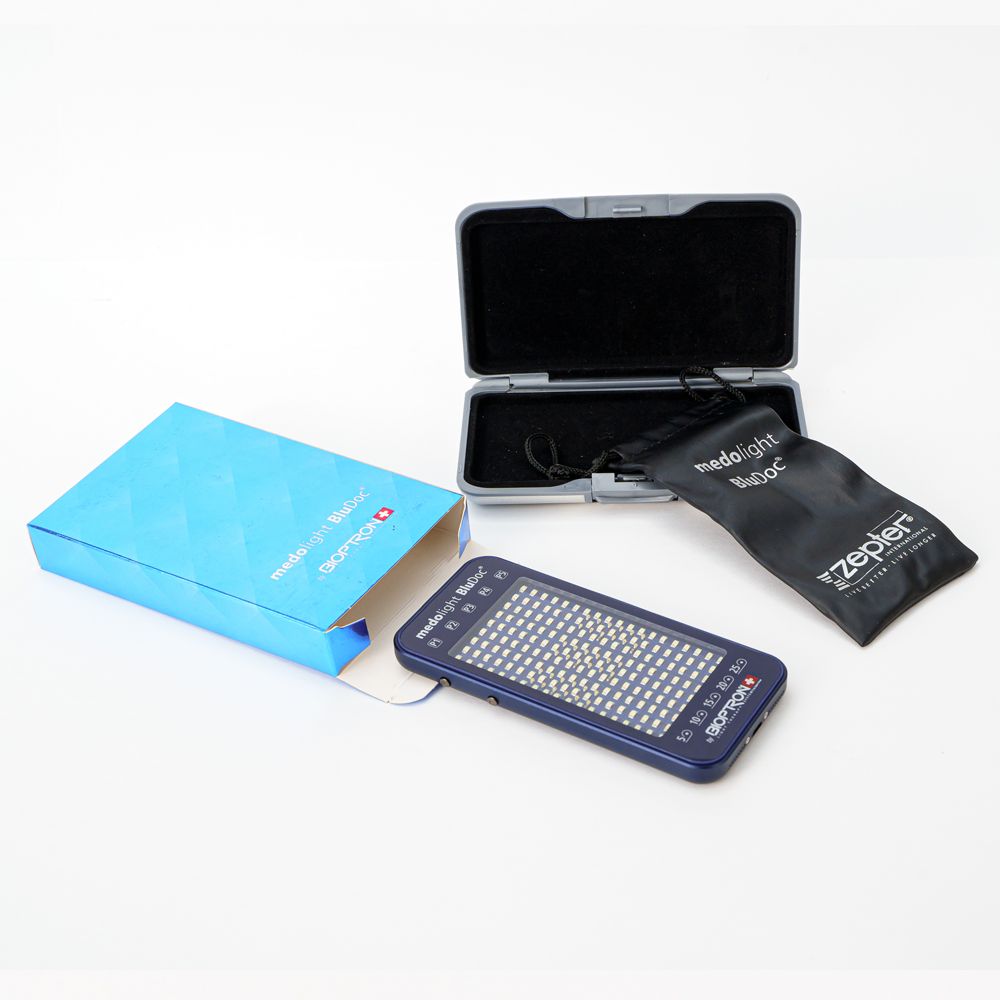 Blaues medolight BluDoc-Gerät, blaue Schachtel, schwarze Tasche und graues Etui. Enthält das Bioptron-Logo.