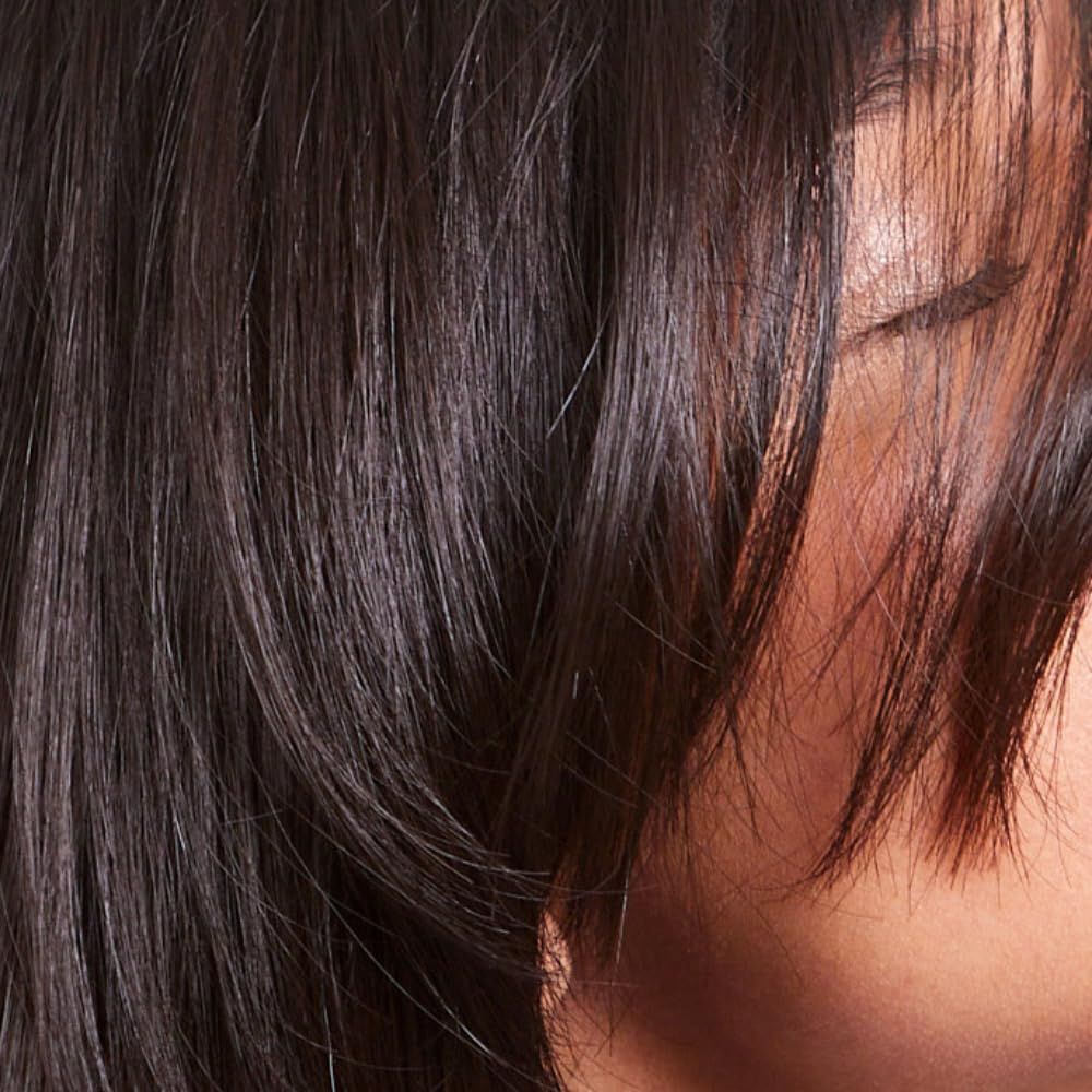 Nahaufnahme einer Person mit dunklem Haar. Das Haar bedeckt einen Teil des Gesichts.