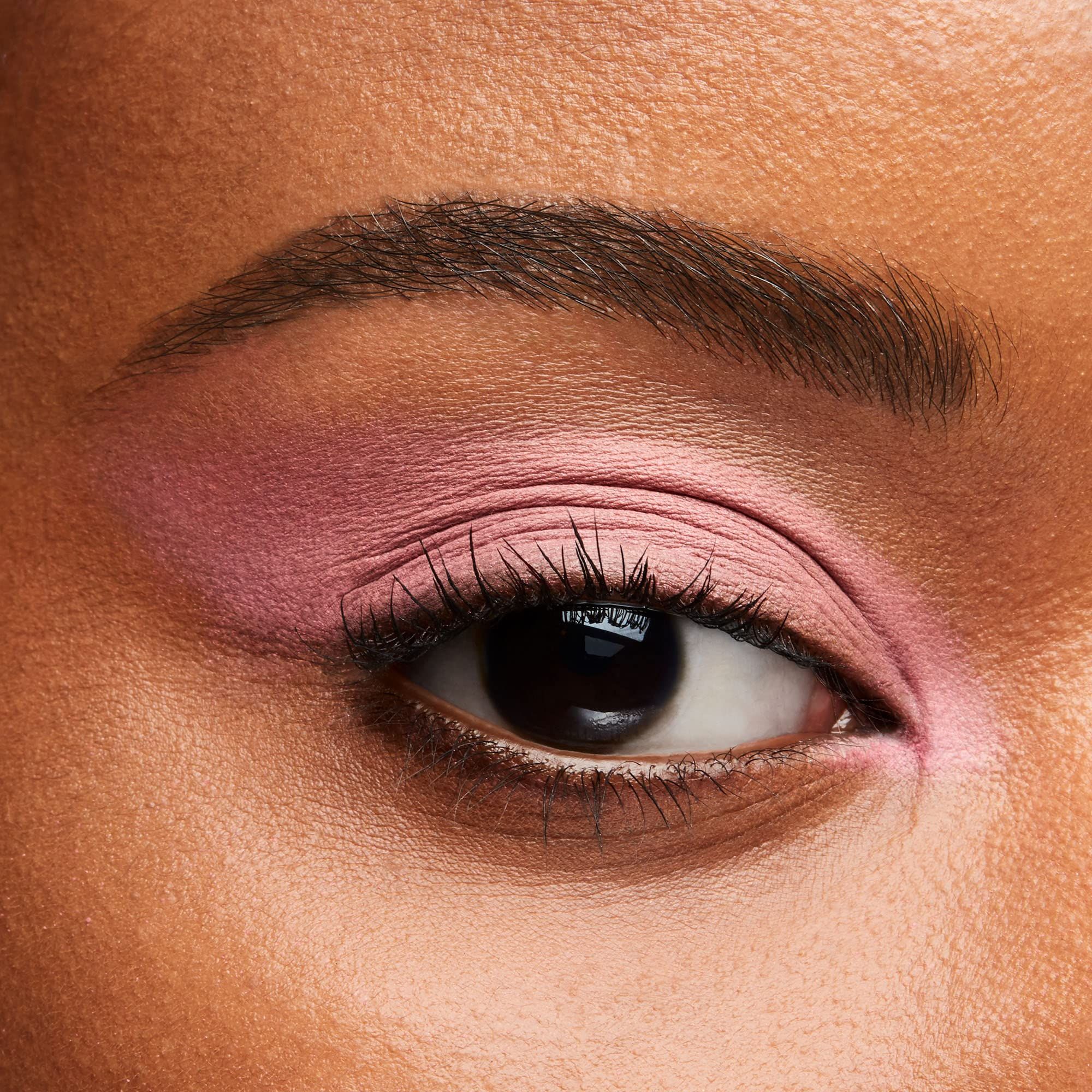 Auge mit rosa Lidschatten. Braune Augenbraue, Wimpern. Nahaufnahme.