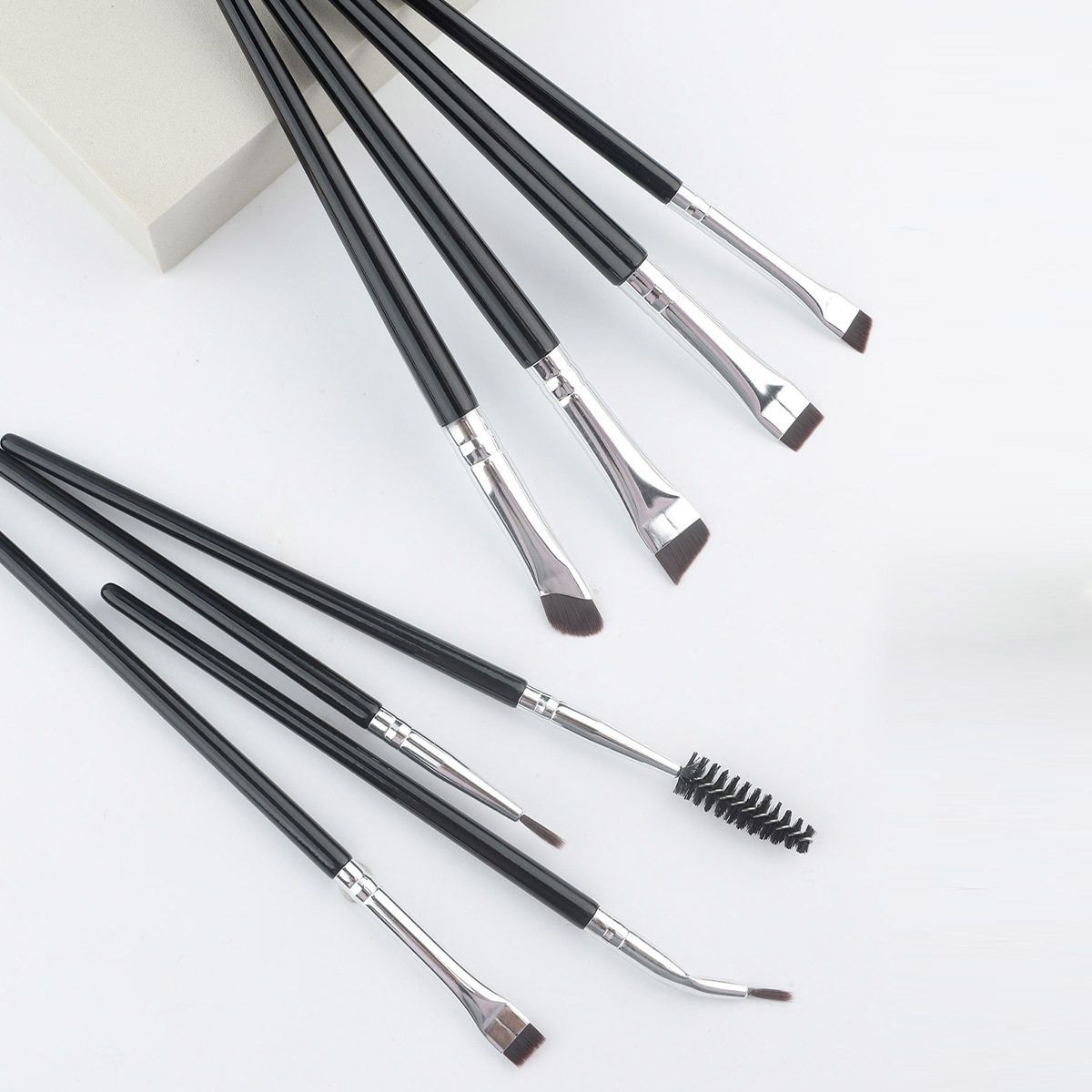Set mit acht schwarzen Make-up-Pinsel mit silbernen Zwingen und verschiedenen Spitzen, darunter abgewinkelte und Bürstenaufsätze.