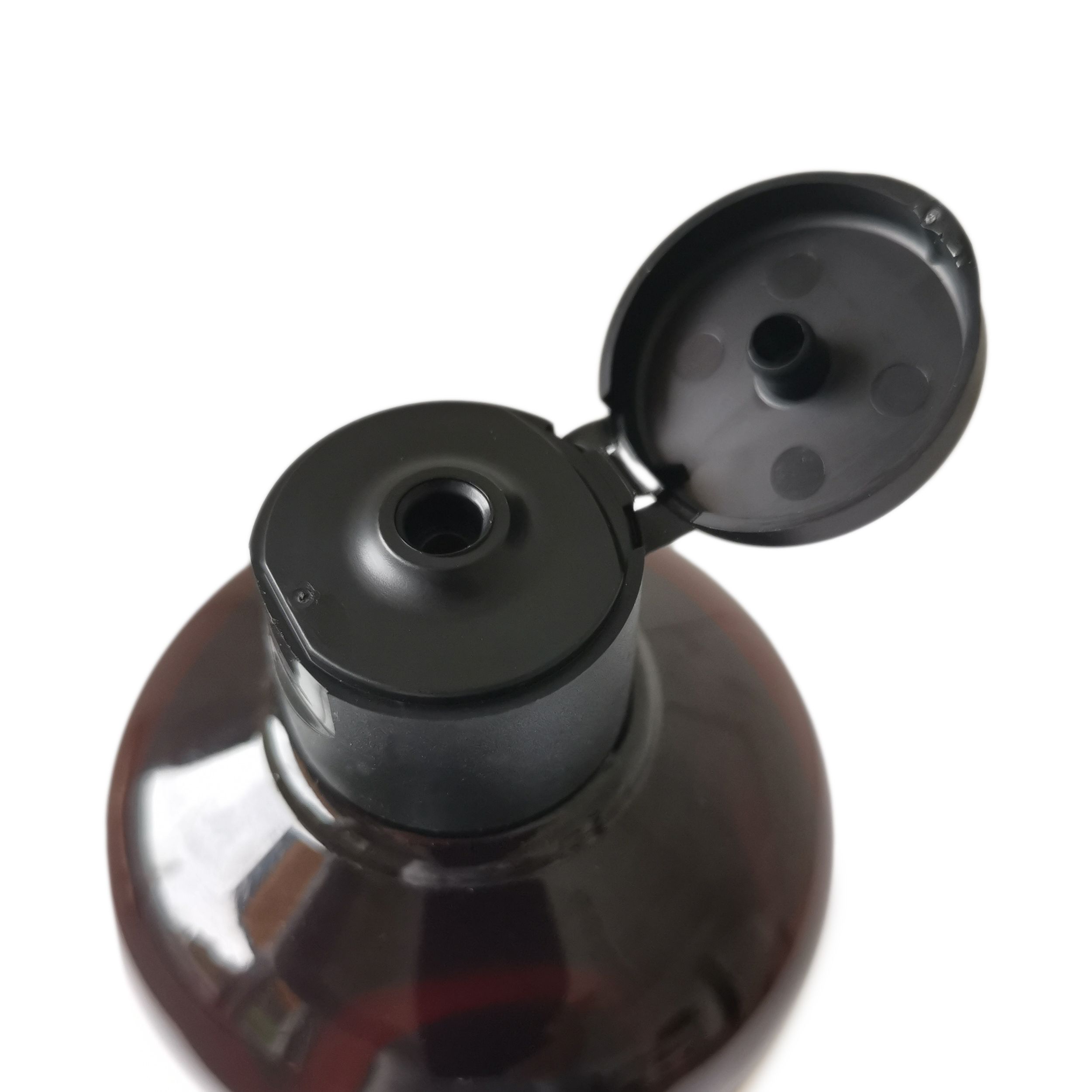 Nahaufnahme eines braunen Flaschenhalses mit schwarzem, geöffnetem Deckel. Der Deckel ist an der Flasche befestigt.