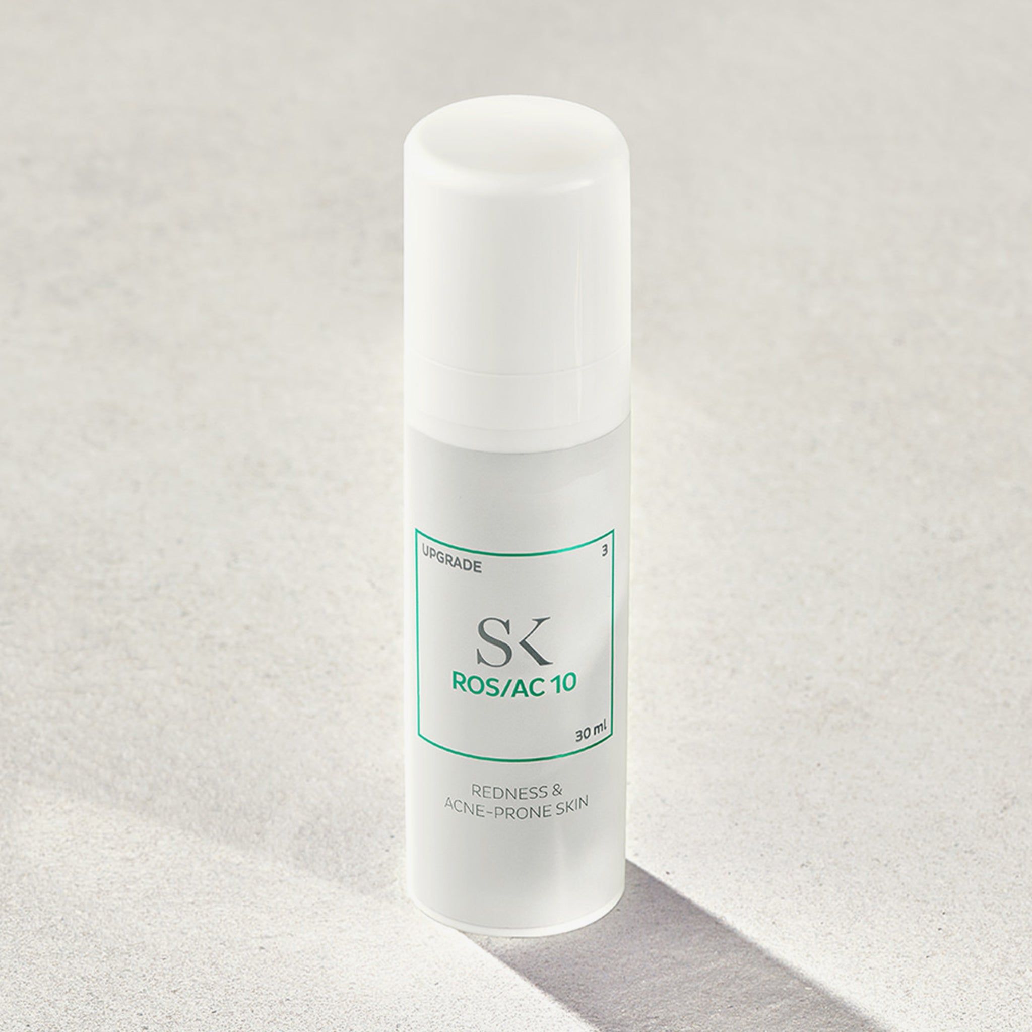 Weißer Flakon mit grünem Etikett. Aufschrift: SK ROS/AC 10, 30 ml. Text: Redness & Acne-Prone Skin. Schatten.