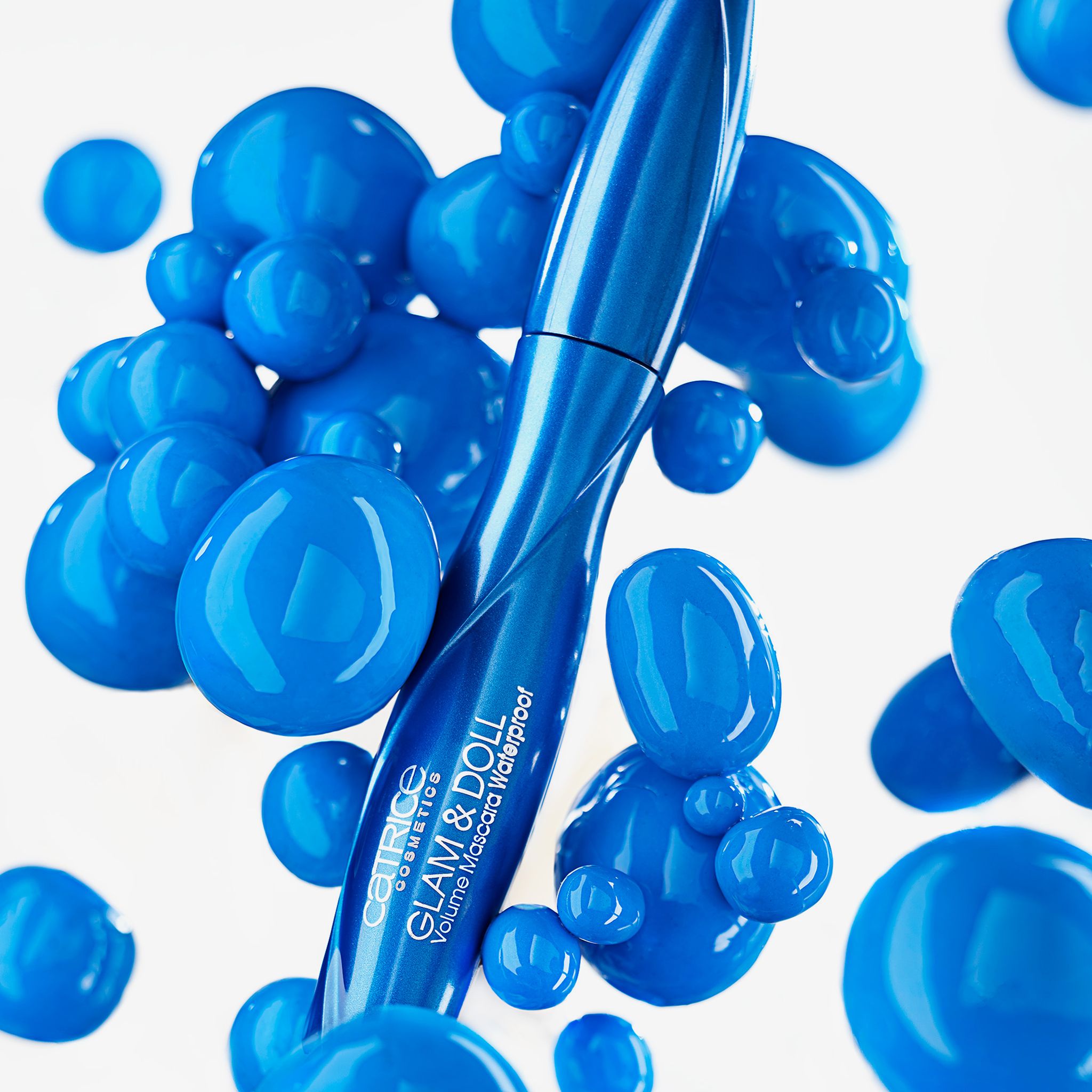 Blaue Mascara-Tube, umgeben von blauen Kugeln. Aufschrift: Catrice Glam & Doll Volume Mascara Waterproof.