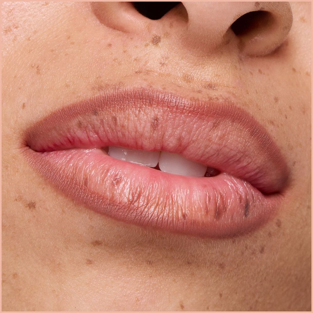 Nahaufnahme von Lippen mit Lippenstift. Haut mit Sommersprossen.