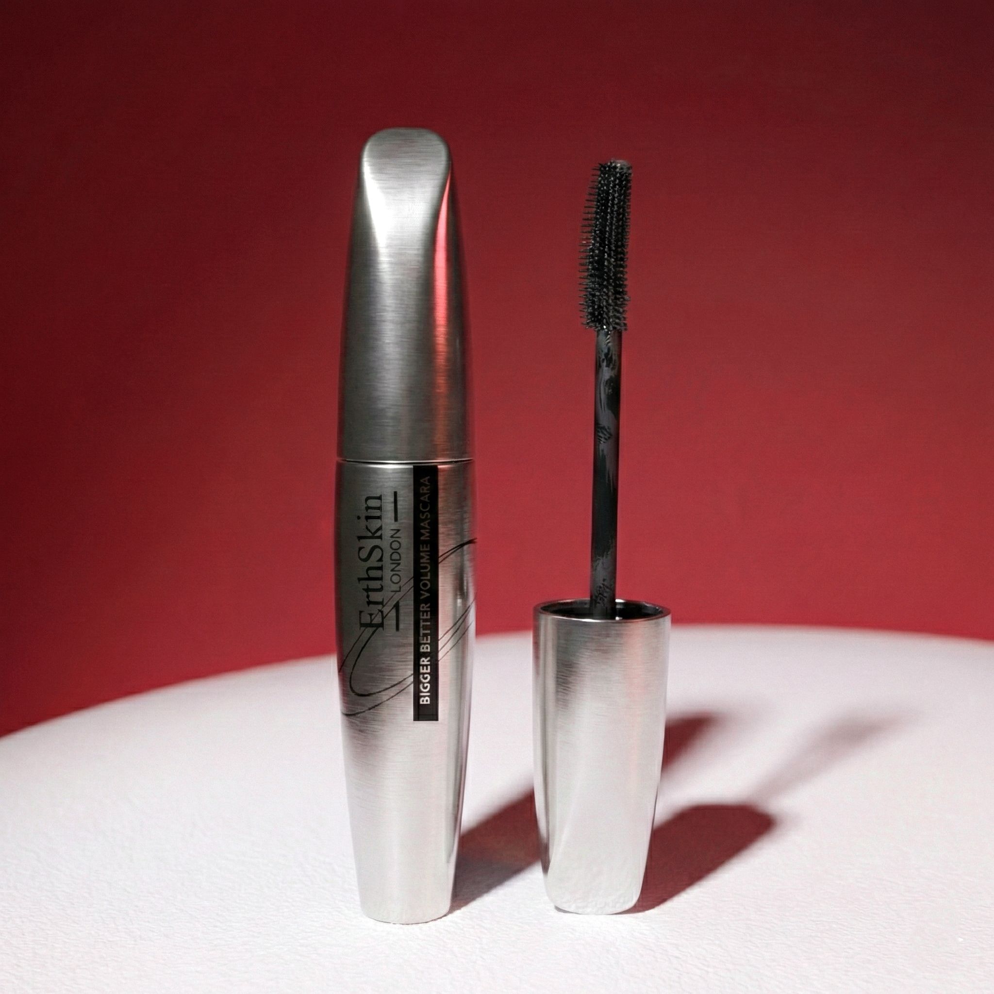 Silberne Mascara-Verpackung und Applikator mit schwarzer Bürste.