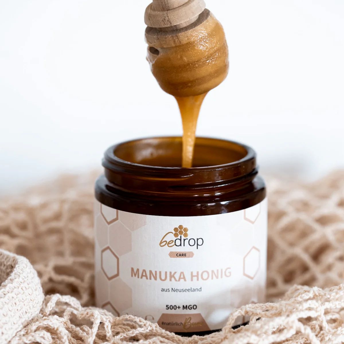Glas Manuka Honig mit Löffel. Honig tropft. Etikett mit Produktinformationen. Auf Netz.