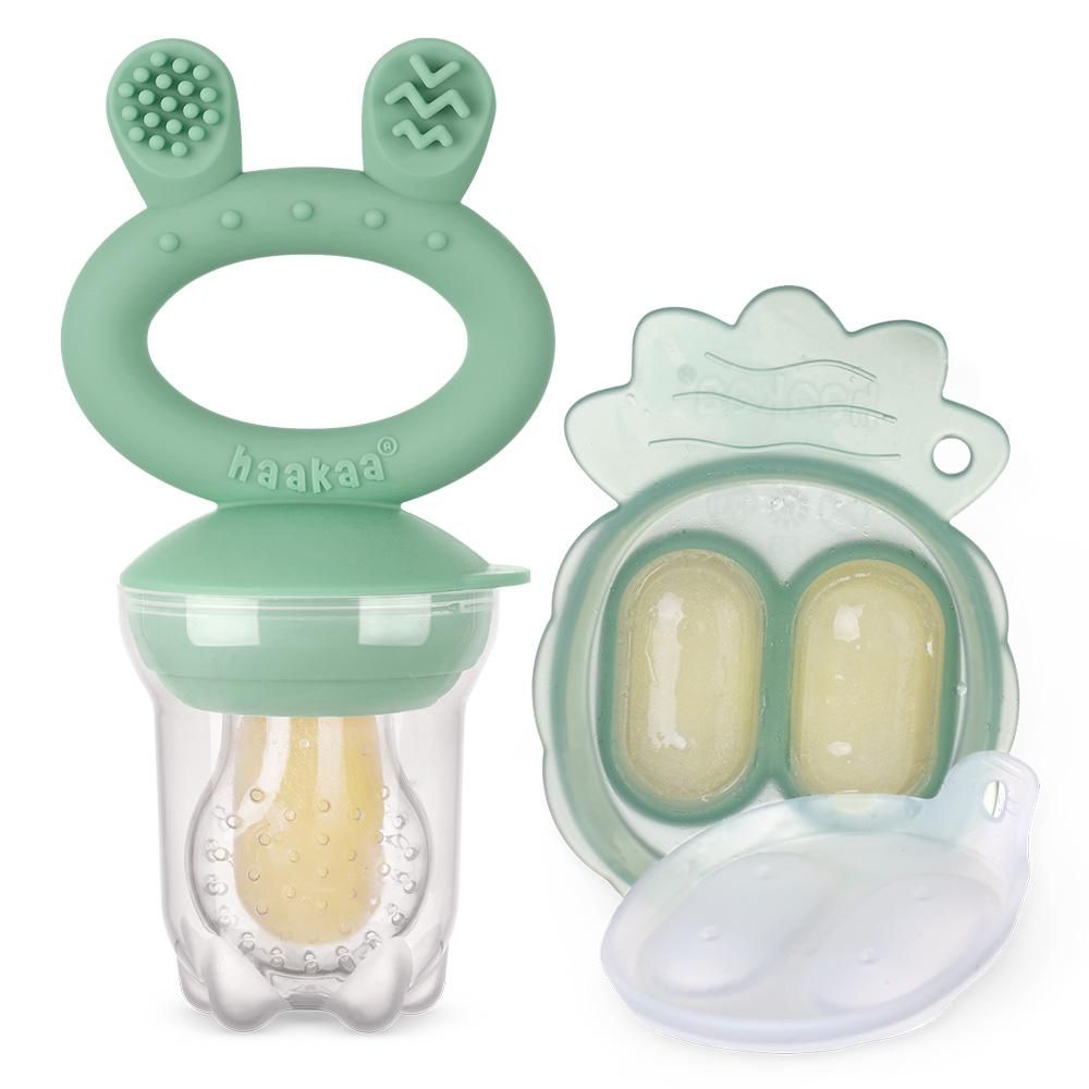 Fruchtsauger und Eiswürfelform. Der Sauger ist grün, die Form ebenfalls. Beide enthalten gelbe Flüssigkeit.