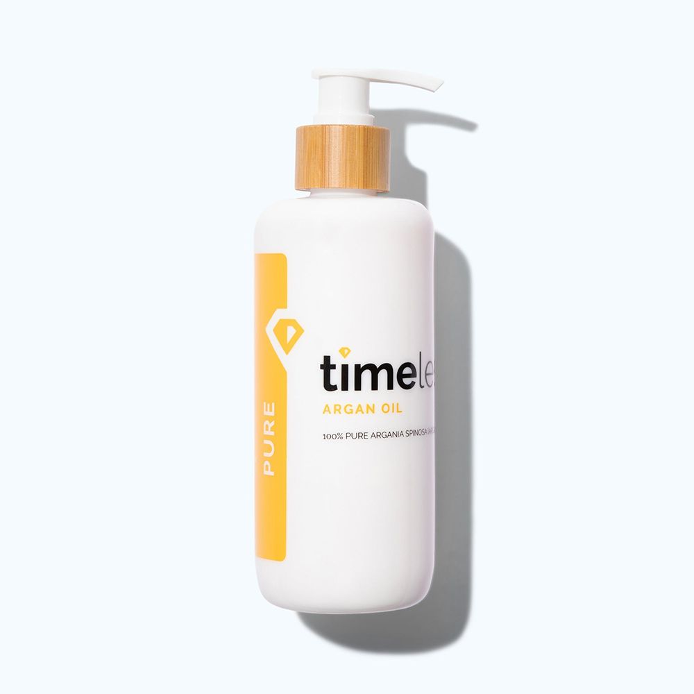Weiße Flasche mit Pumpe und Holzdeckel. Aufschrift: timeless Argan Oil. Gelber Aufkleber mit "PURE".