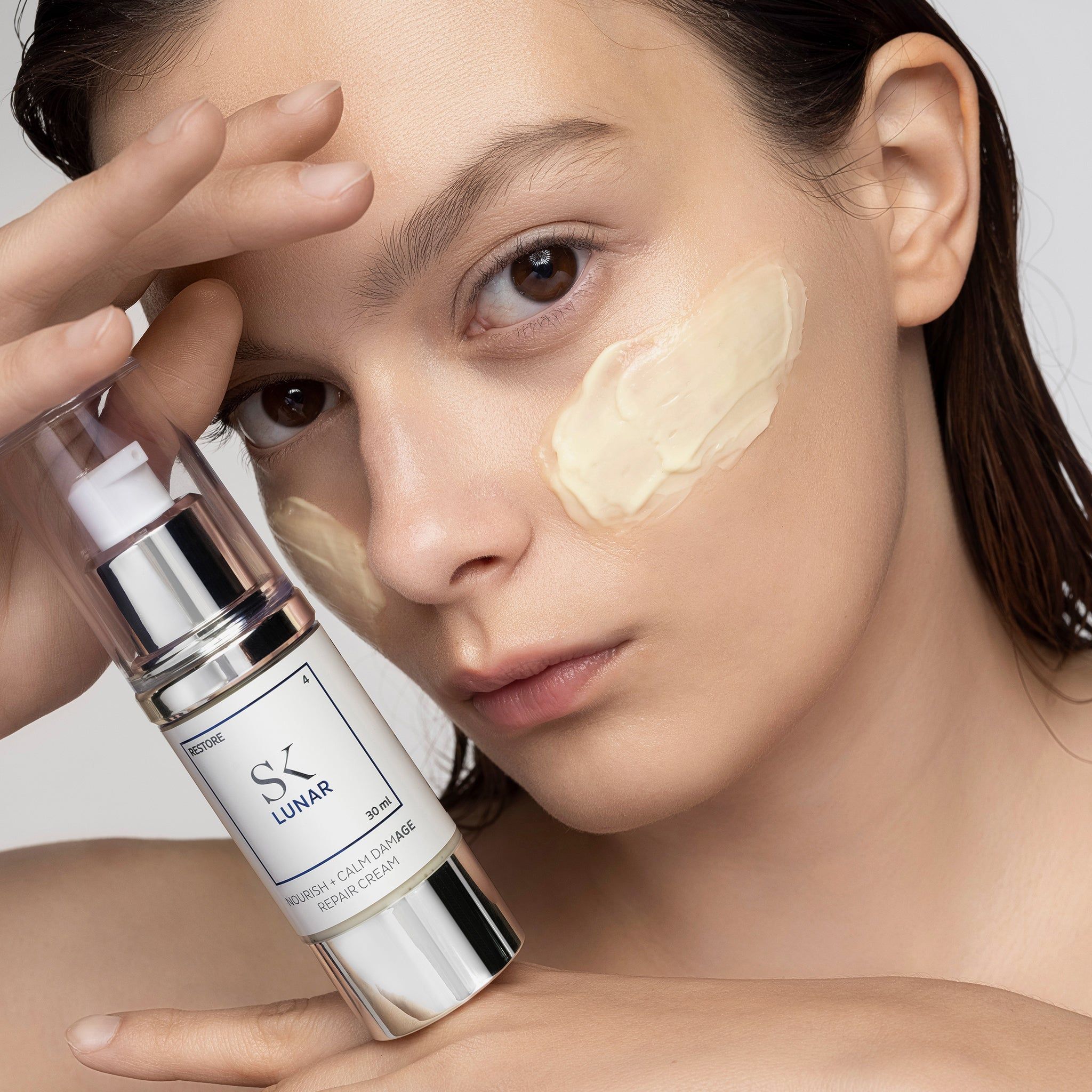 Frau mit Creme auf dem Gesicht. Creme-Spender in der Hand. Aufschrift: SK Lunar, 30 ml.