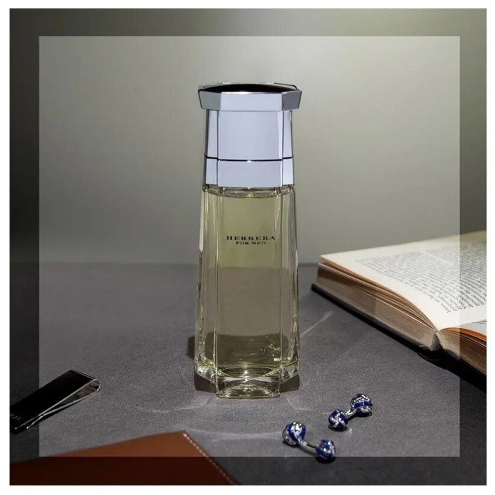 Glasflakon mit silbernem Deckel, neben Buch, Manschettenknöpfen und Geldscheinklammer auf Tisch.