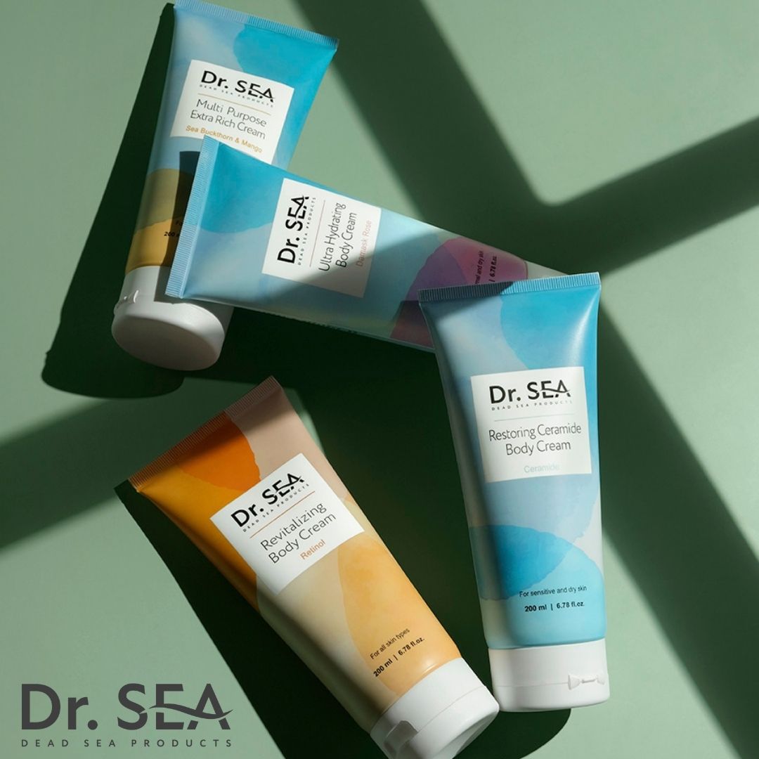Vier Tuben DR. SEA Körpercreme. Verschiedene Designs: Ultra Hydrating, Restoring Ceramide, Revitalizing Body Cream. Grünem Hintergrund.