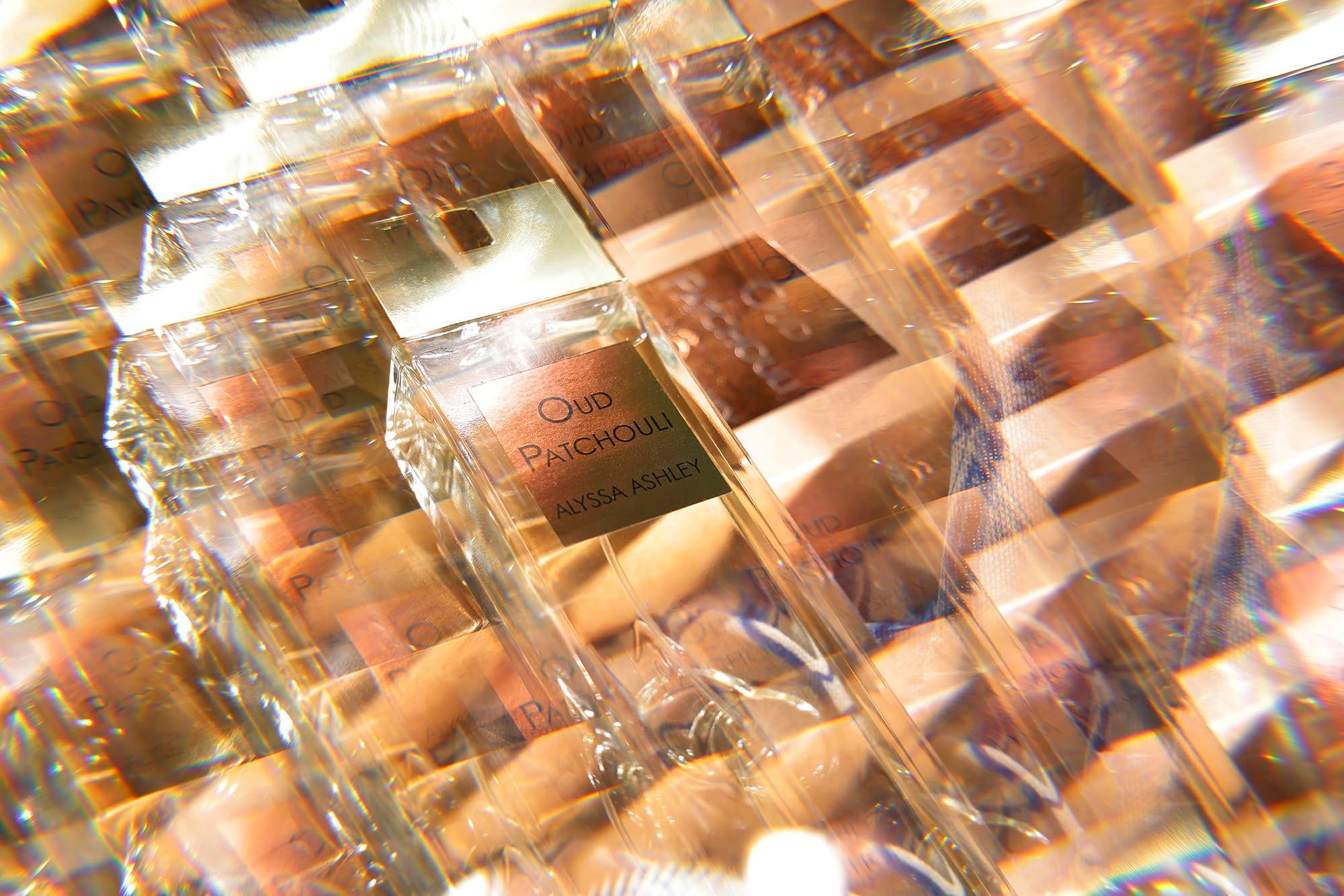 Verpackte Alyssa Ashley Oud Patchouli Flakons. Aufschrift Oud Patchouli, Alyssa Ashley. Mehrere Flakons in Folie verpackt.