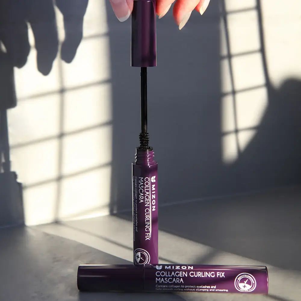 Mascara-Tube und Bürste. Aufschrift: MIZON Collagen Curling Fix Mascara. Lila Tube, schwarze Bürste.