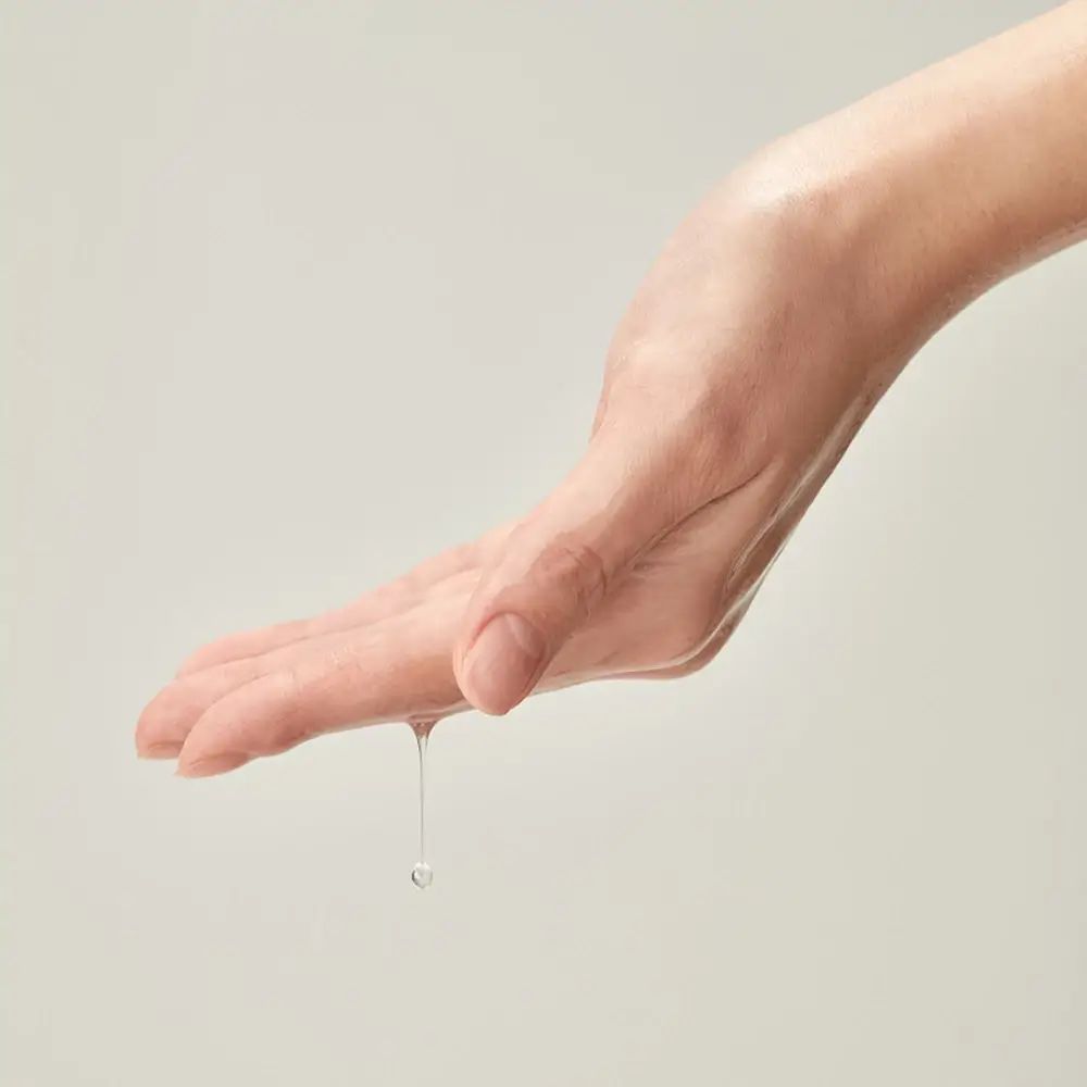 Hand mit Tropfen Flüssigkeit. Flüssigkeit tropft von der Handfläche.