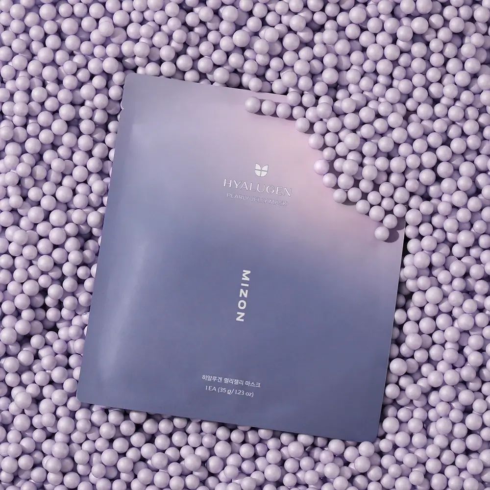 Verpackung der MIZON Hyalugen Pearly Jelly Mask auf lila Kugeln. Logo und Produktname sind sichtbar.