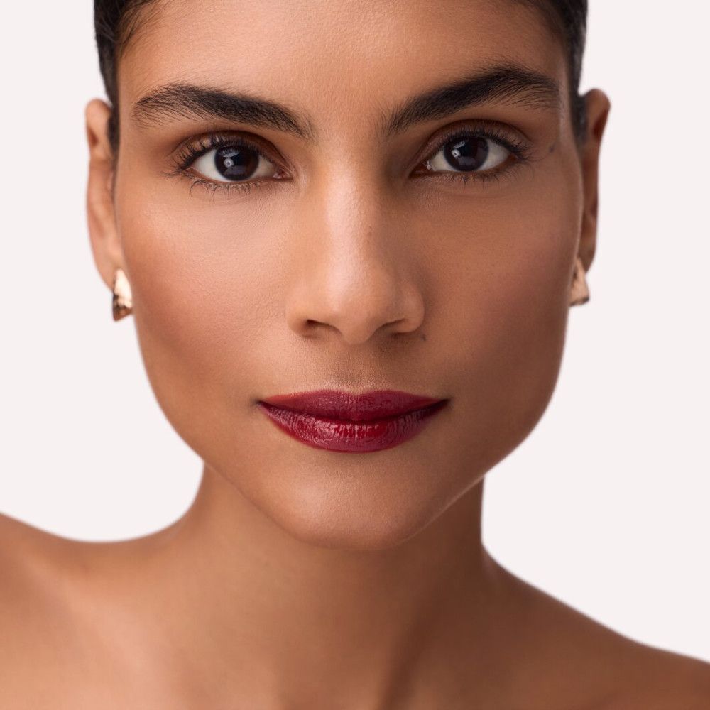 Porträt einer Frau mit dunkelrotem Catrice Colour Glaze Lip Tint auf den Lippen. Hautton und Augenbrauen sichtbar.