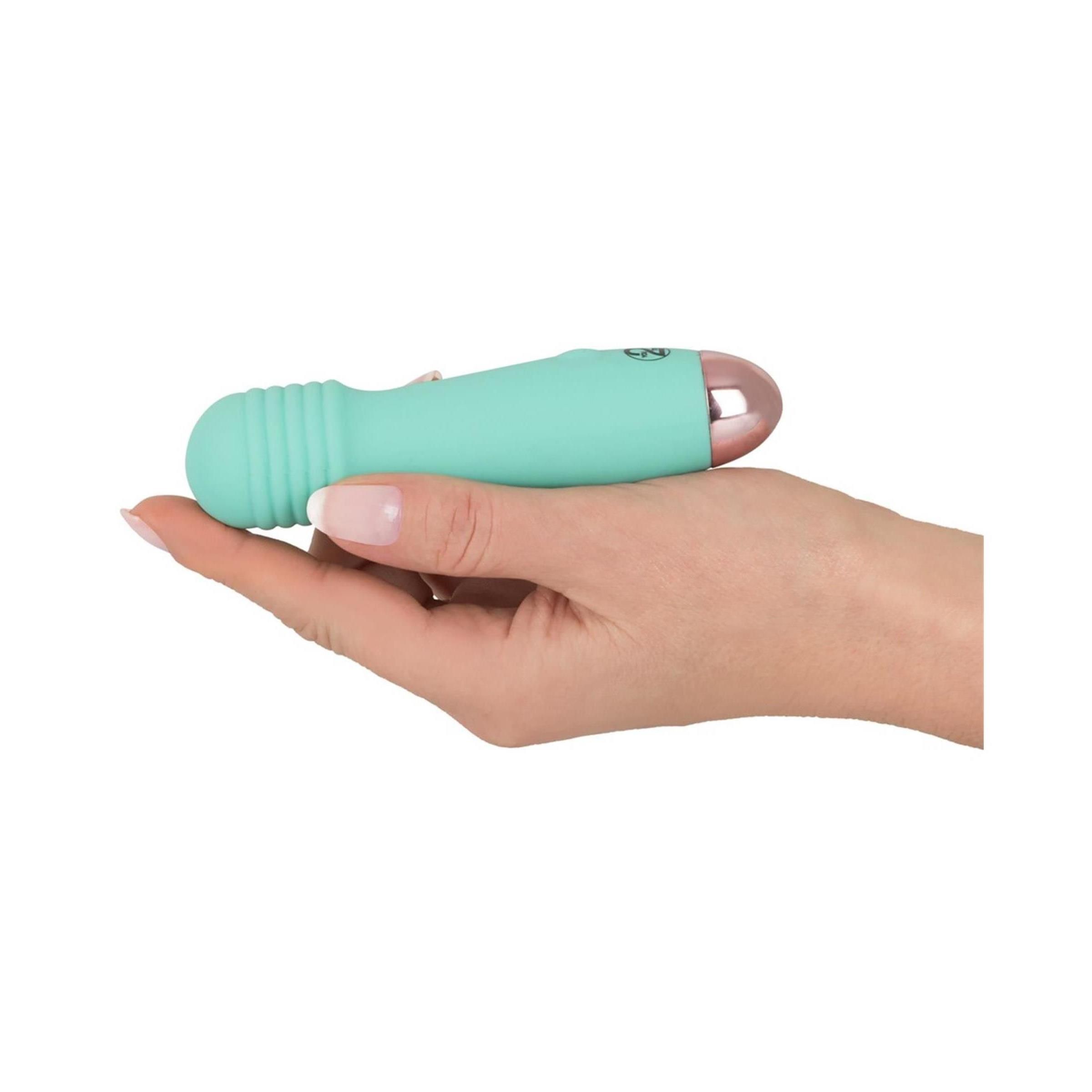 Türkisfarbener Vibrator in einer Hand gehalten. Geriffelte Spitze, rosa Spitze sichtbar.