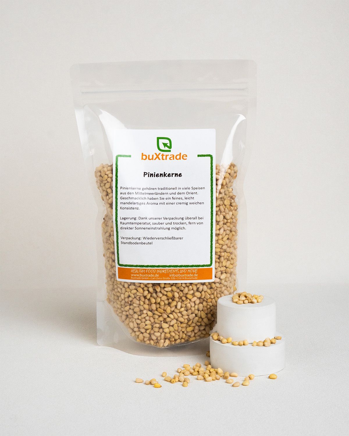 Verpackung von buXtrade Pinienkernen. Beutel mit Etikett und Produktname. Daneben Podest mit Pinienkernen.