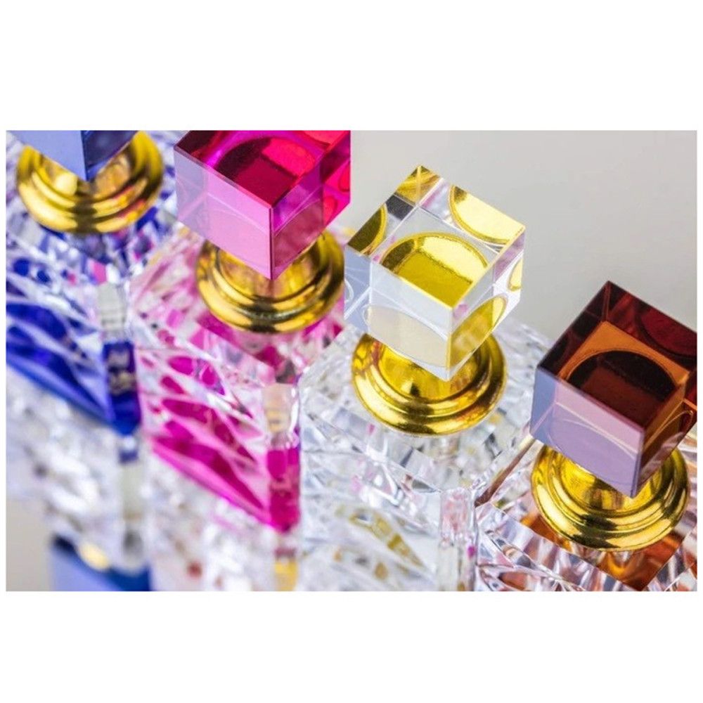 Reihe von Parfümflakons mit farbigen Deckeln. Facettierte Glasbehälter mit goldenen Details.