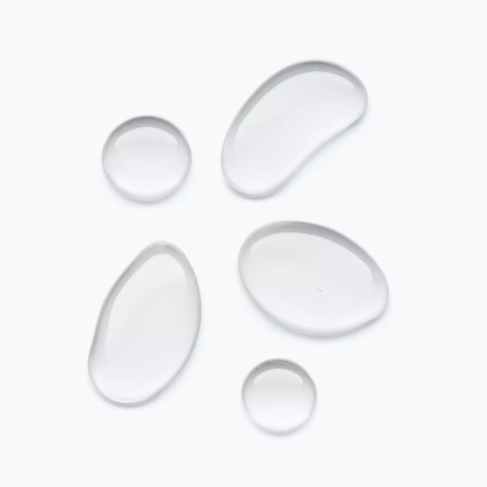 Fünf klare, tropfenförmige Flüssigkeitstropfen auf weißem Hintergrund. Unterschiedliche Größen und Formen.