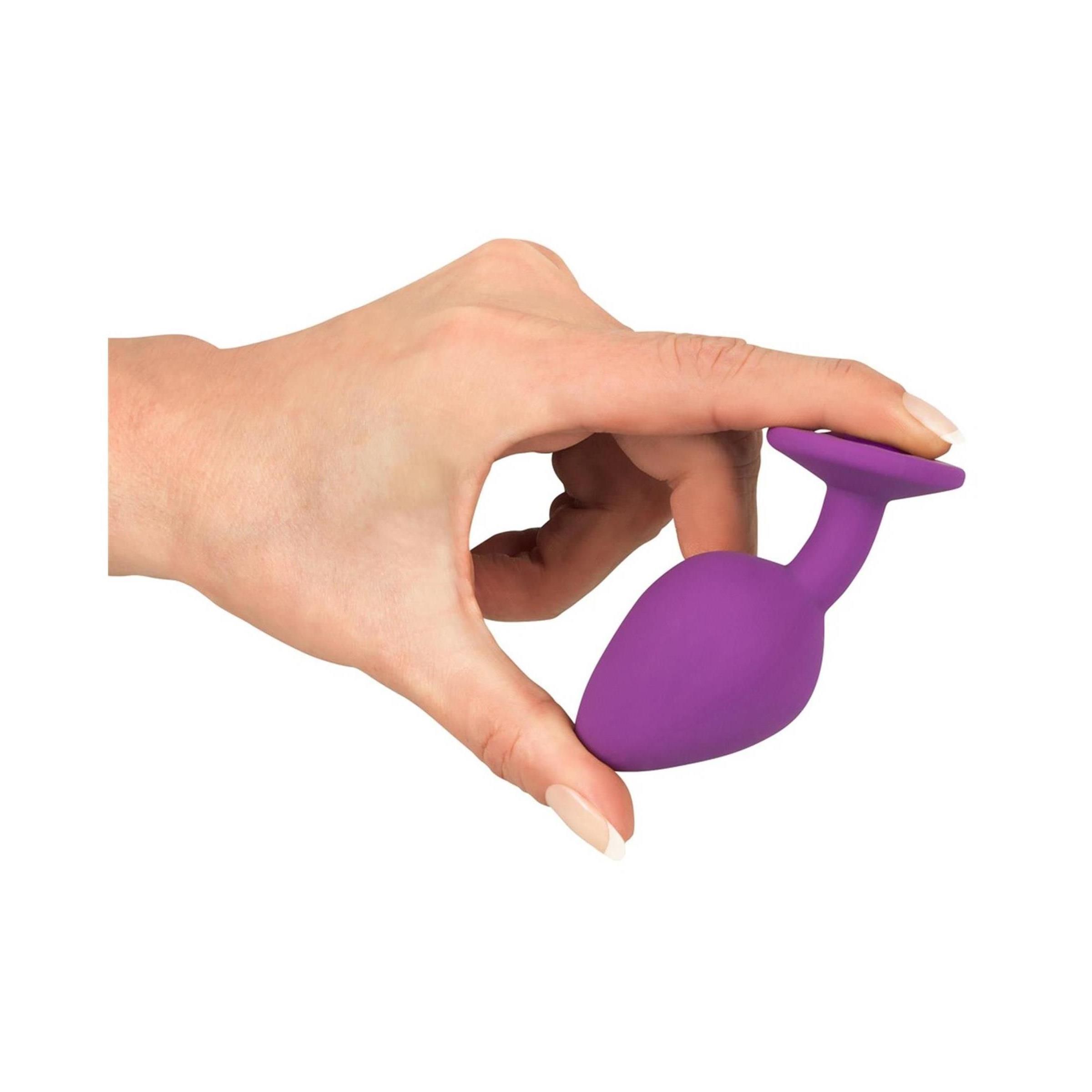 Hand hält lila Plug. Konische Form, runde Basis. Nahaufnahme.