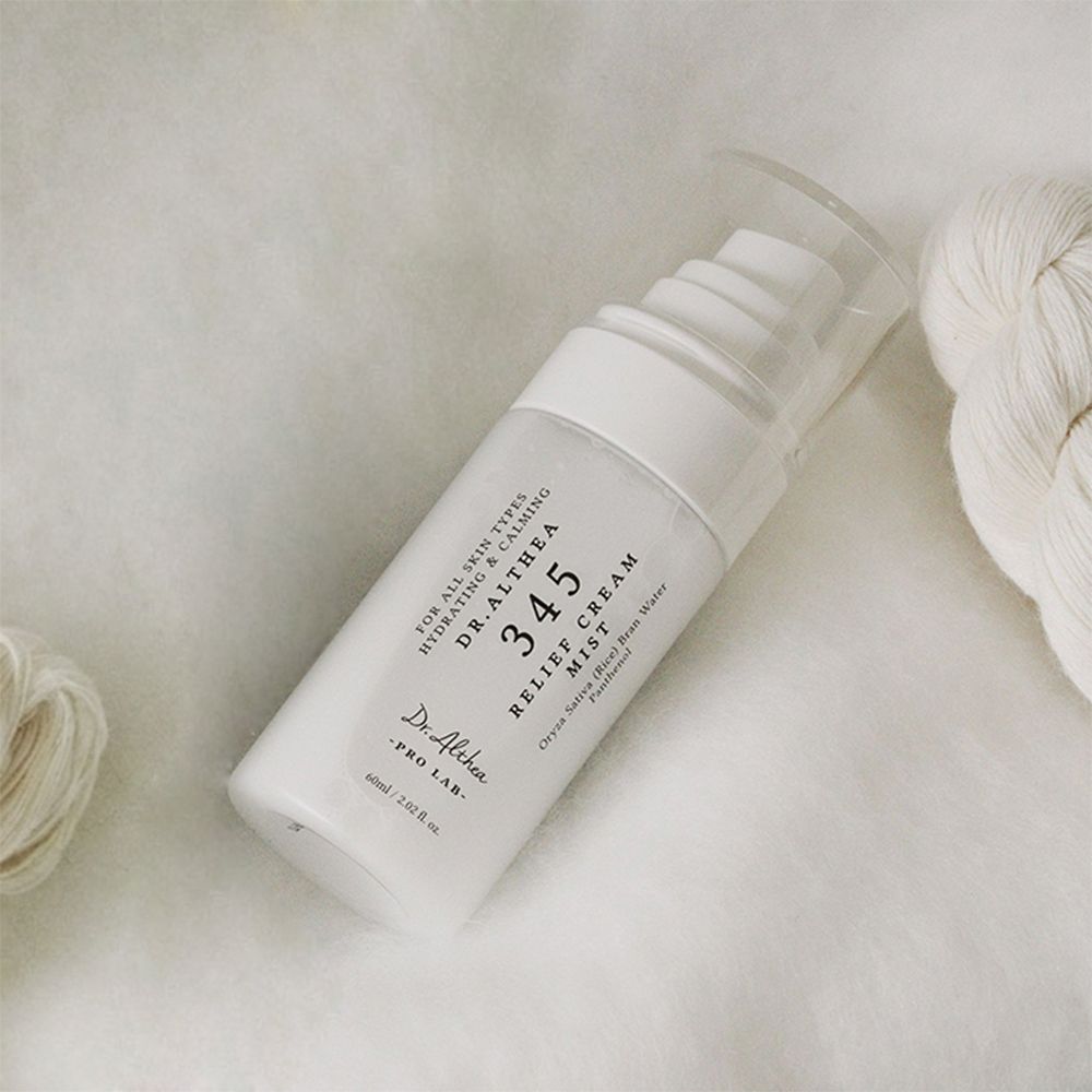 Weiße Sprühflasche mit transparentem Deckel. Aufschrift: 345 Relief Cream Mist, Dr. Althea. Liegt auf hellem Stoff.