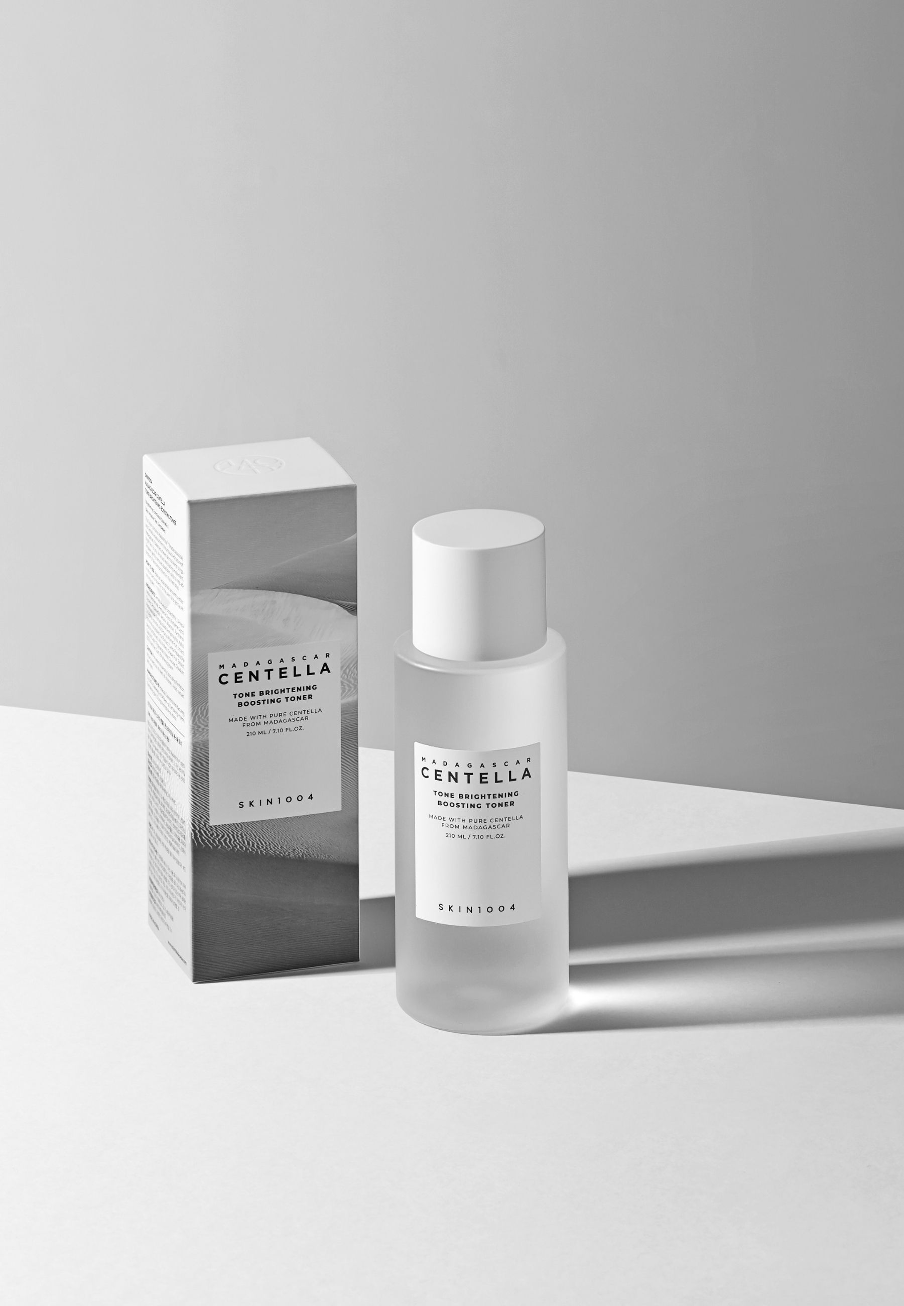 Produktflasche und Verpackung. Flasche mit Etikett. Verpackung mit Produktnamen und Marke SKIN1004. Schatten.