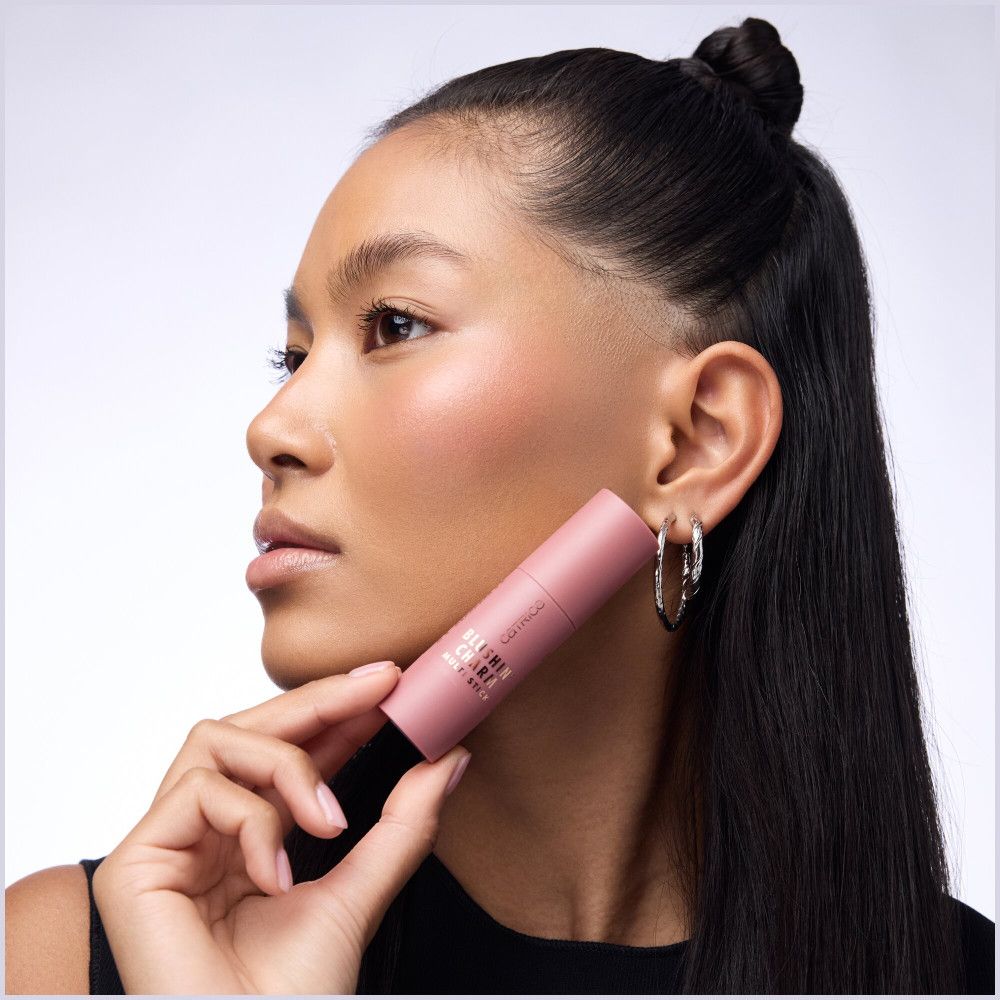 Frau hält einen Catrice Blush Stick. Produktname und Marke sichtbar. Rosa Farbton.