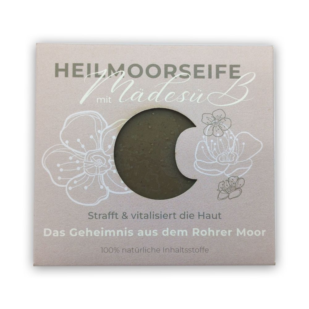 Verpackung mit Heilmoorseife mit Mädesüß. Sichtbares Produkt in Halbmondform. Text: Strafft & vitalisiert die Haut, 100% natürliche Inhaltsstoffe.
