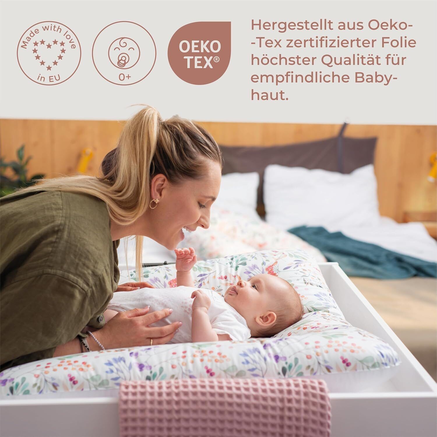 Frau und Baby auf Wickelauflage. Oeko-Tex-Zertifizierung. Text: Hergestellt aus Oeko-Tex zertifizierter Folie.