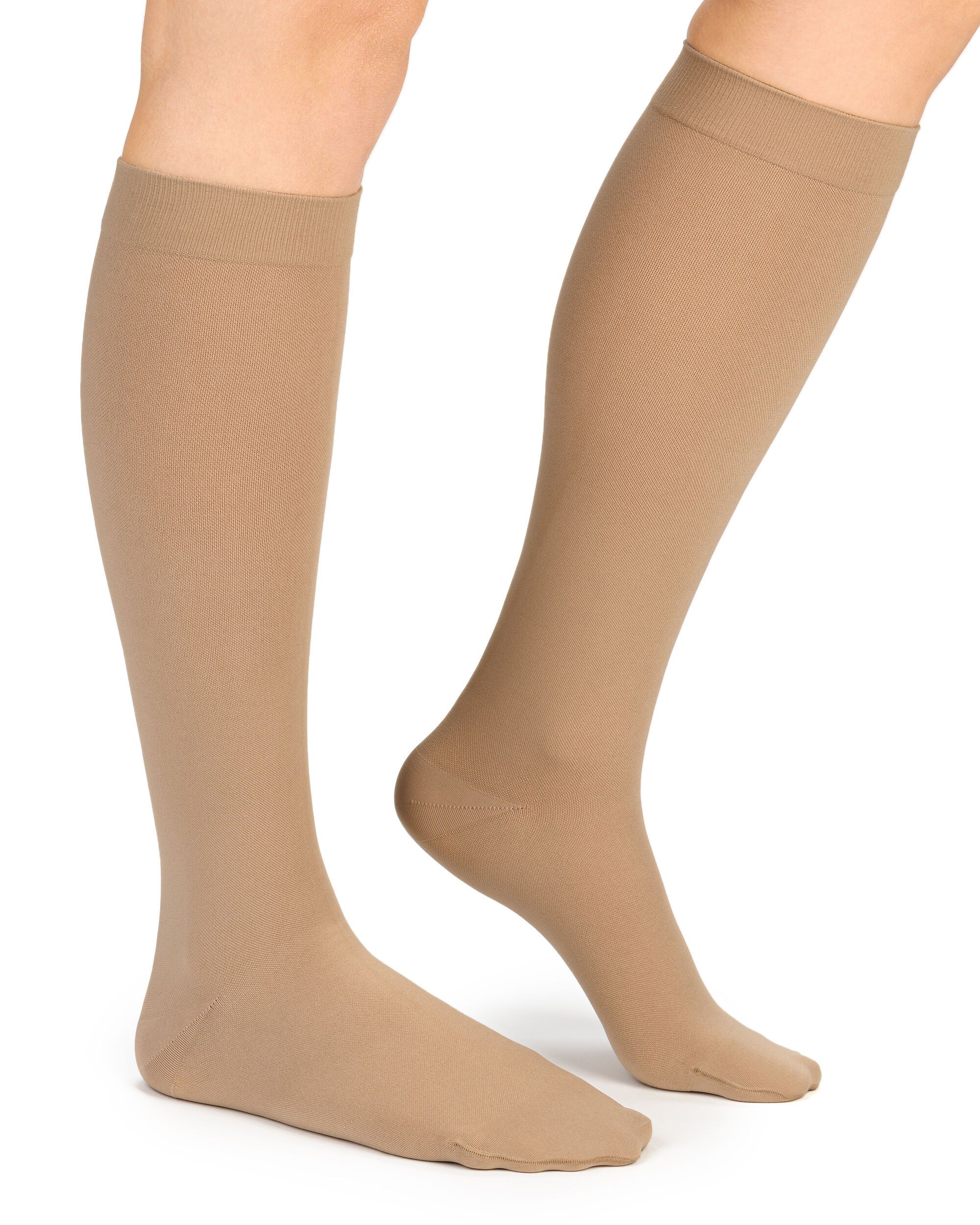 Beige Kompressionsstrümpfe am Bein. Blick von der Seite, beide Beine sichtbar. Strümpfe reichen bis zum Knie.