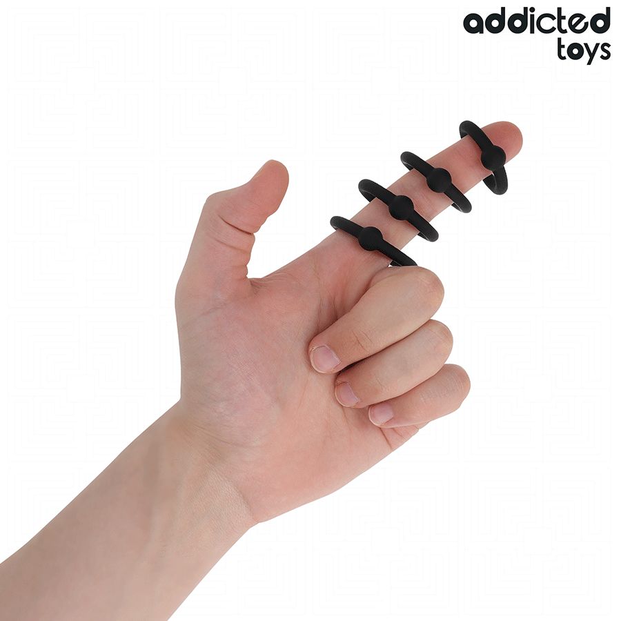 Hand mit vier schwarzen Fingerringen. Jeder Ring hat eine kleine Erhebung. Marke: Addicted Toys.