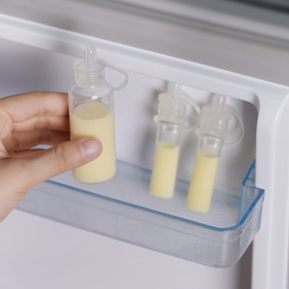 Zwei transparente Behälter mit Flüssigkeit, gehalten von einer Hand. Im Kühlschrank.