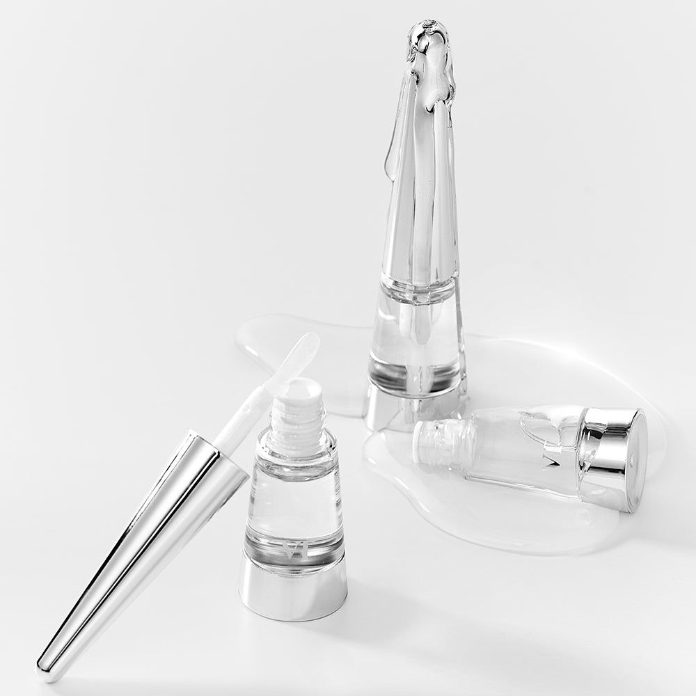 Drei Lippen-Plumper-Flakons mit Applikatoren und Produkt. Silberfarbene Deckel, transparente Behälter.