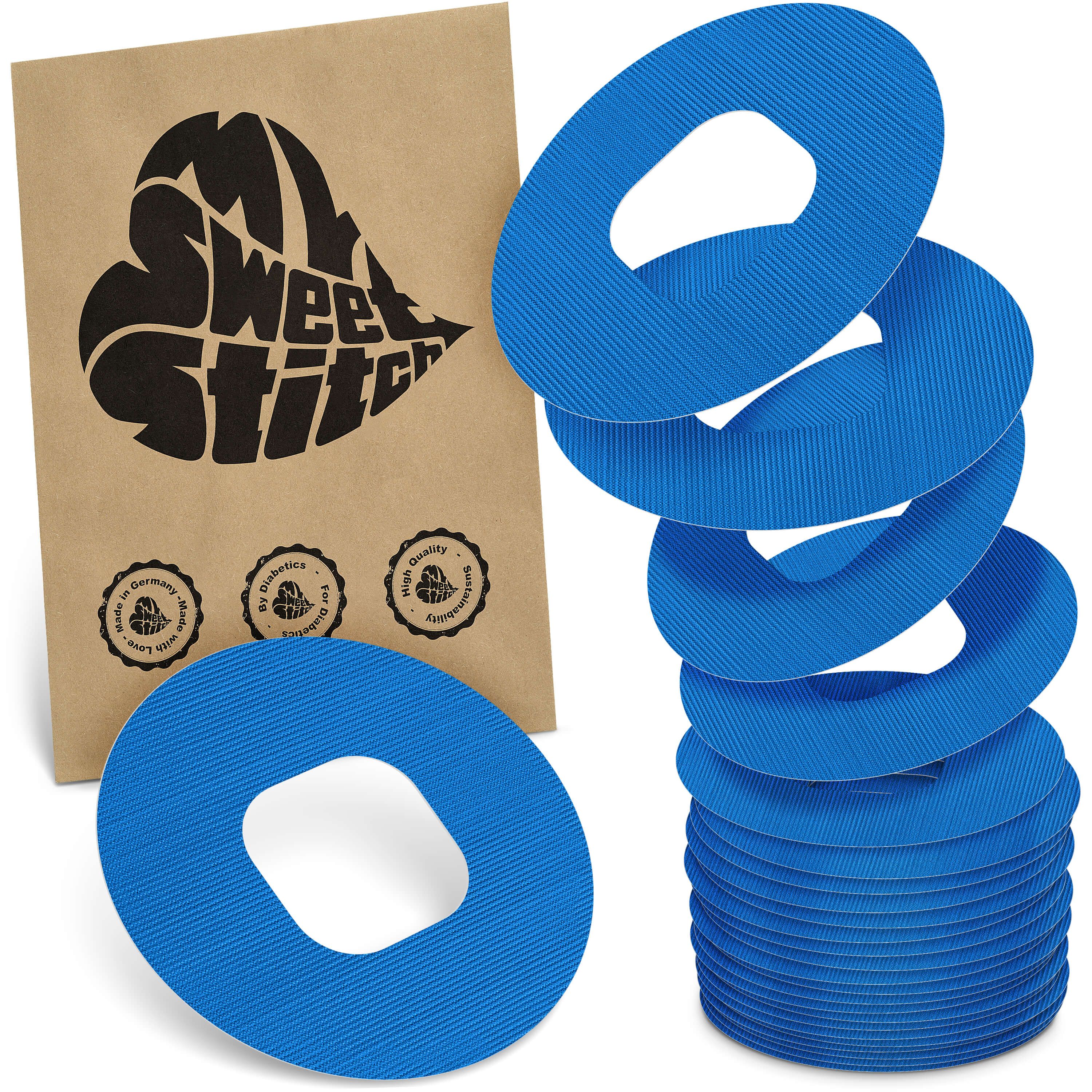 Blaue, ringförmige Pflaster mit ovaler Aussparung. Neben einer braunen Verpackung mit Logo. Mehrere Pflaster gestapelt.
