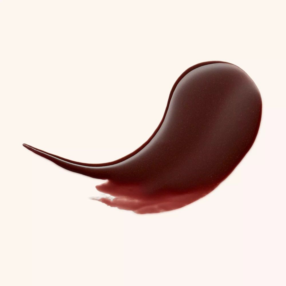 Brauner Lippenbalsam-Abstrich. Glänzende Textur in Tropfenform. Auf hellem Hintergrund.