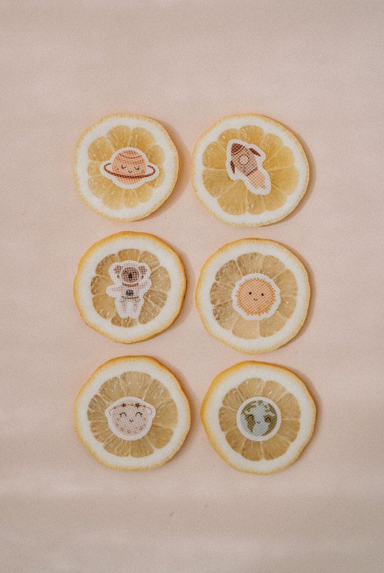 Sechs Zitronenscheiben mit pieksmichnicht Stickern. Motive: Planet, Rakete, Koala, Sonne, Stern, Erde.
