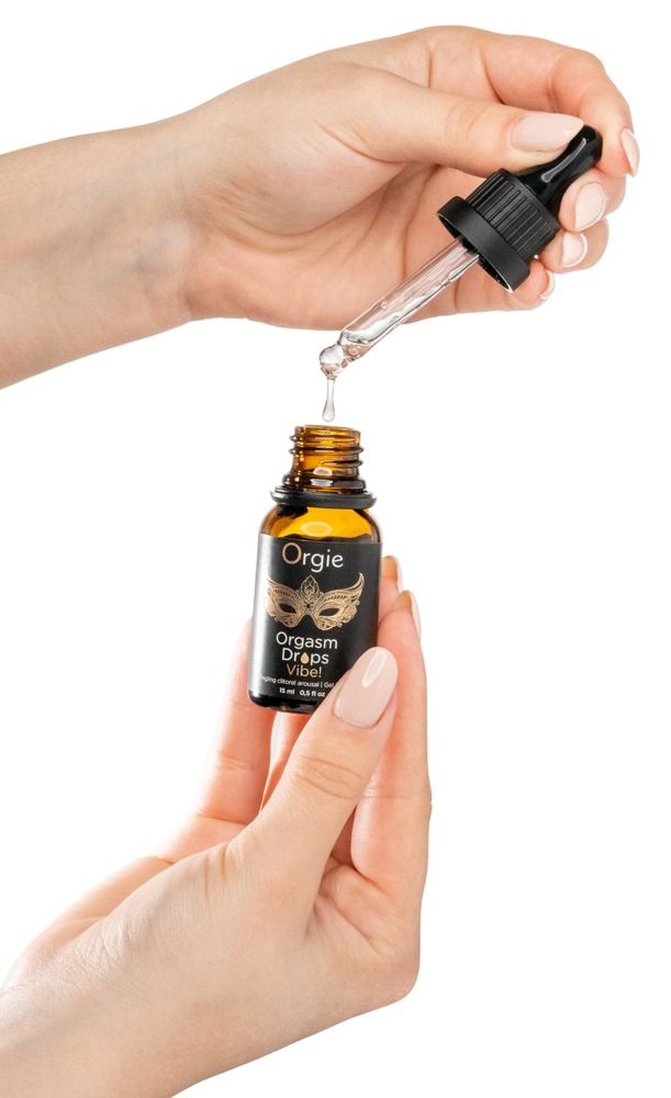 Hände halten eine braune Flasche mit Tropfer. Produktname: Orgie Orgasm Drops Vibe! Tropfen fallen aus dem Tropfer.