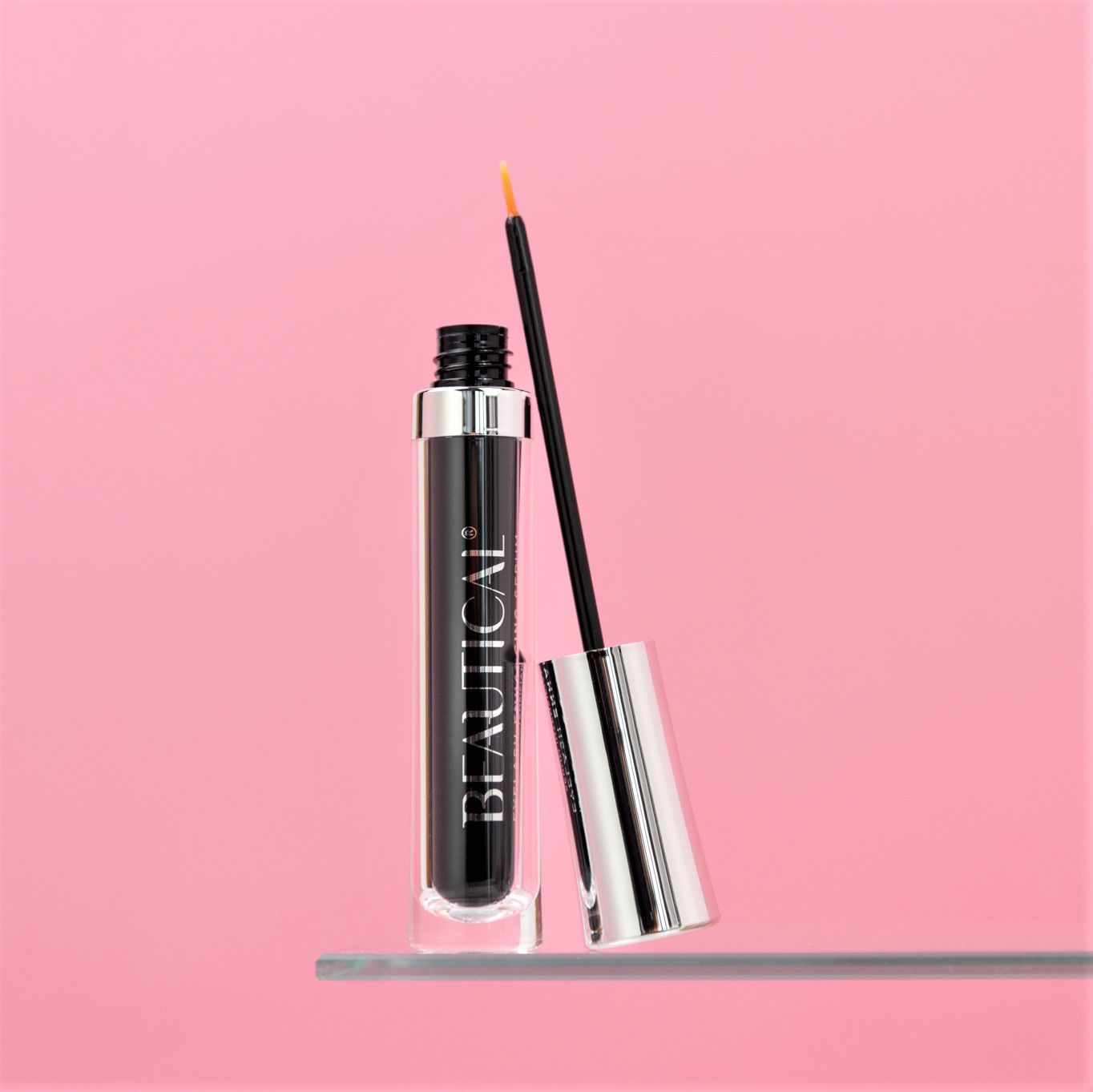 BEAUTICAL Wimpernserum. Schwarze Flasche mit Applikator. Rosa Hintergrund.