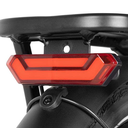 Rücklicht an einem Fahrrad. Rotes Licht. Schwarzer Gepäckträger und Kotflügel.