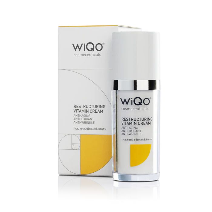 Eine weiße Flasche und Schachtel mit dem Logo WiQo. Auf der Flasche steht "Restructuring Vitamin Cream".