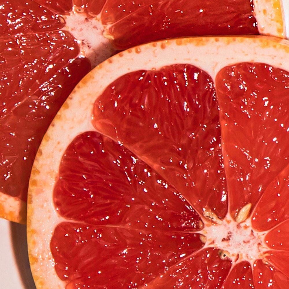 Nahaufnahme von zwei Grapefruit-Hälften. Rotes Fruchtfleisch mit hellrosa Schale. Sichtbare Textur und Saftigkeit.