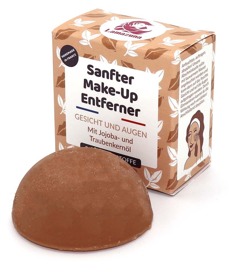 Brauner, halbkugelförmiger Make-up-Entferner neben Kartonverpackung. Aufschrift: Sanfter Make-Up Entferner, Gesicht und Augen. Marke: Lamazuna.