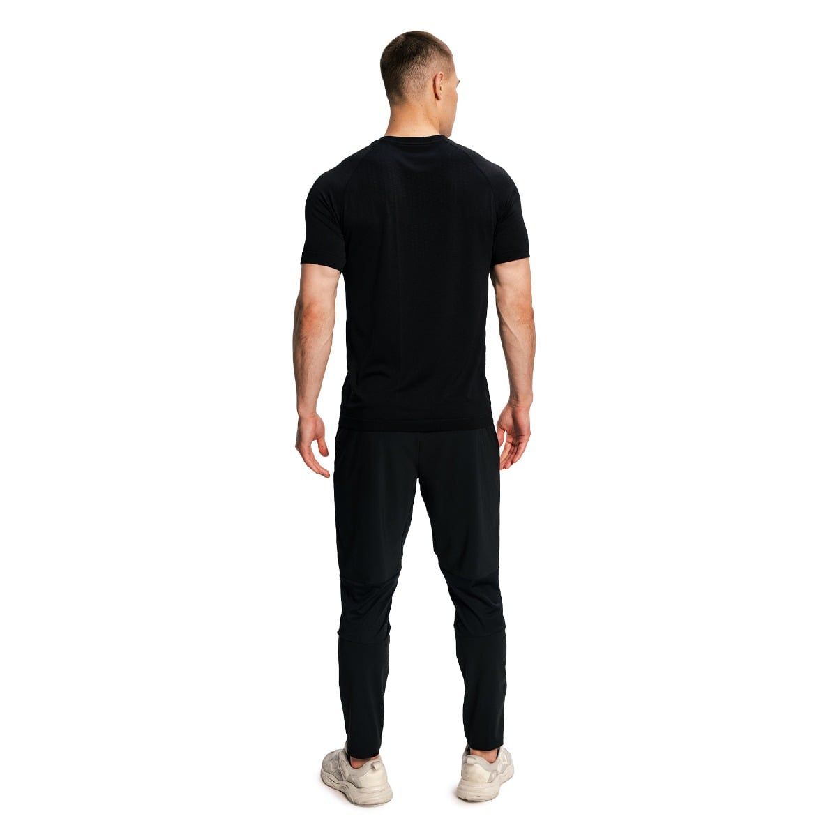 Mann von hinten in schwarzem Kurzarm-T-Shirt und Sporthose, weiße Turnschuhe.