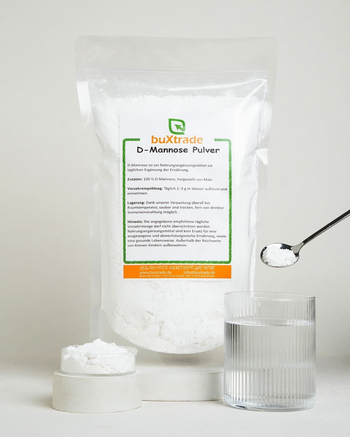 Bags of buxtrade D-Mannose powder with a spoon and glass of water.