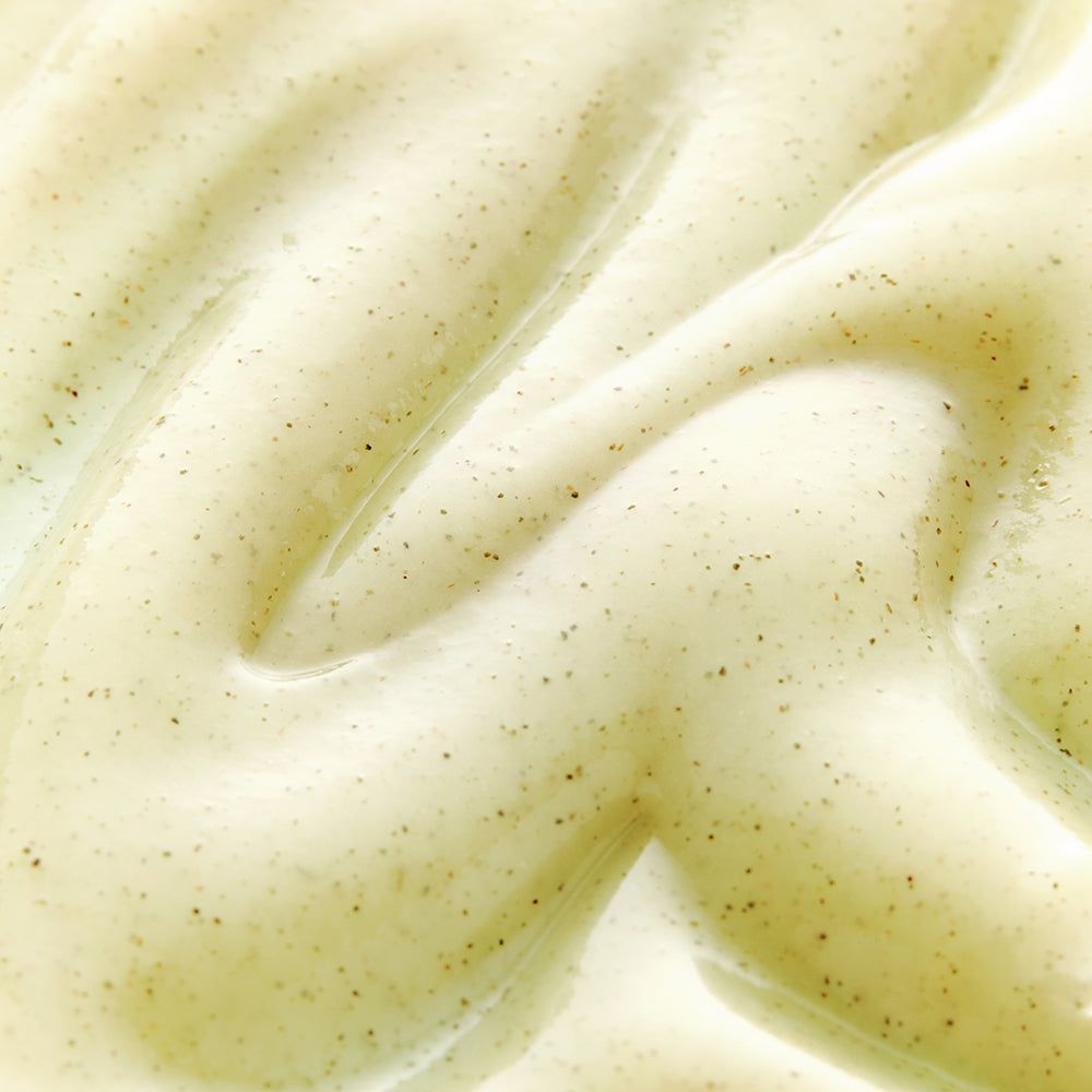 Nahaufnahme von Gel. Cremefarbene Textur mit kleinen dunklen Partikeln.