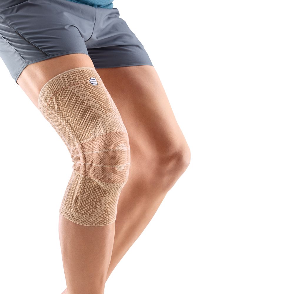 Kniebandage, beige, am Bein getragen. Mesh-Gewebe, Kniebereich verstärkt. Logo am oberen Rand. Person in Sportkleidung.